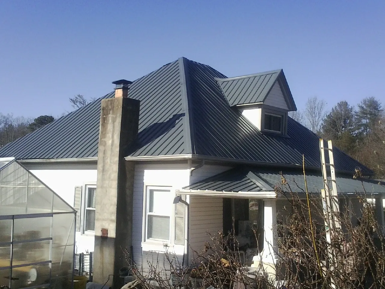 Dark blue standing seam metal roof on a white farmhouse with dormer — Slate & Tile Roof Repair by Roofing Brothers in El Centro