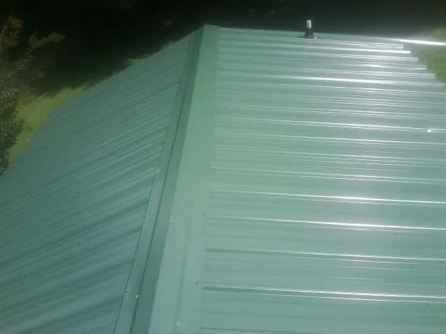New green metal panels meeting at the ridge of a roof — Flat Roof Repair work by our crew in El Centro