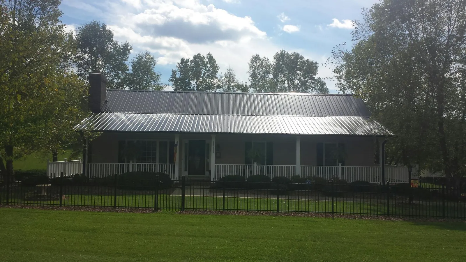 Gray metal roof on a brick ranch with a full width front porch — Gutter Guard Installation work by our crew in El Centro